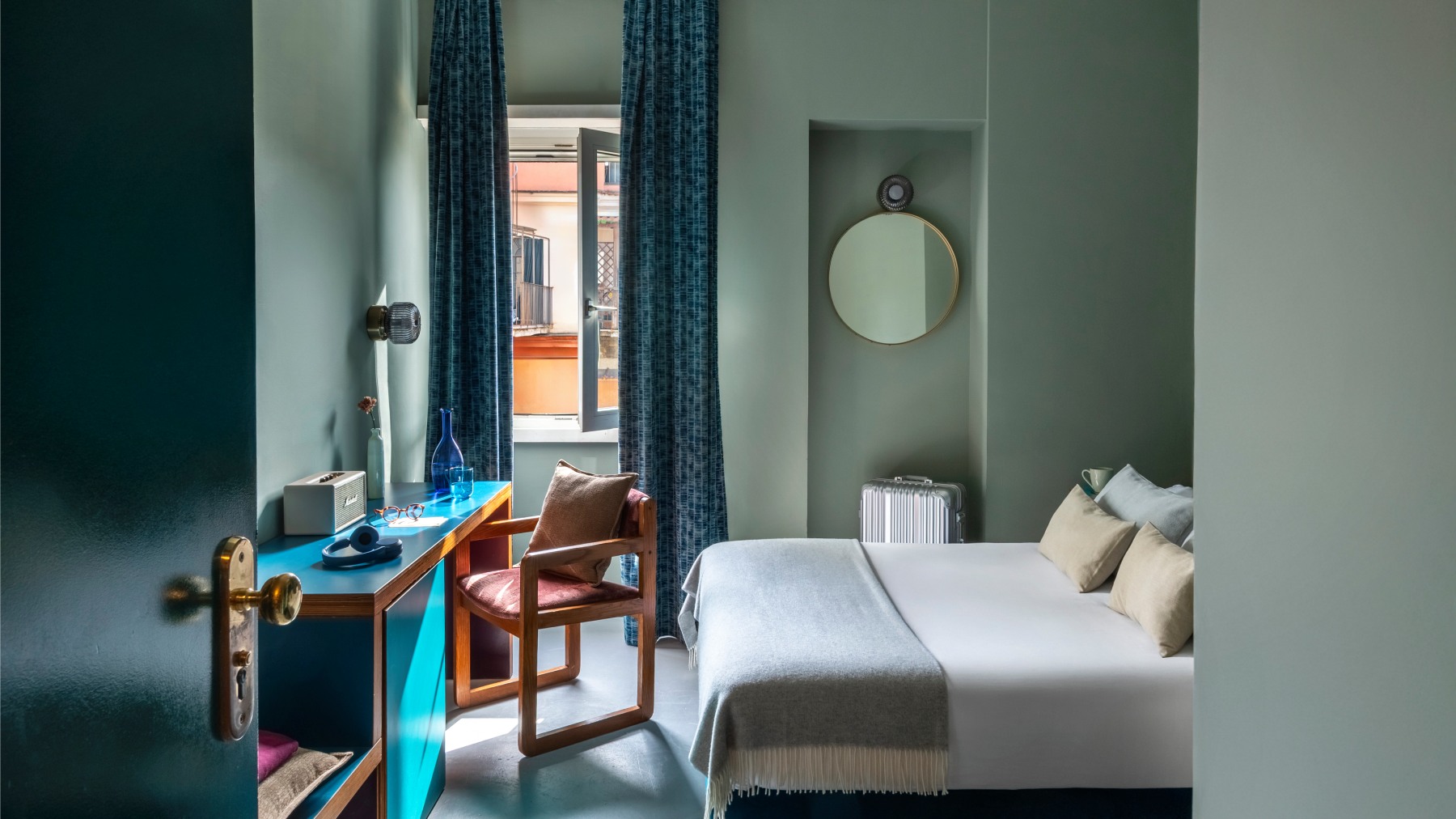 Interior view of a modern teal hotel room with blue desk and window - Hotel Milani, BZAR hotels in Rome